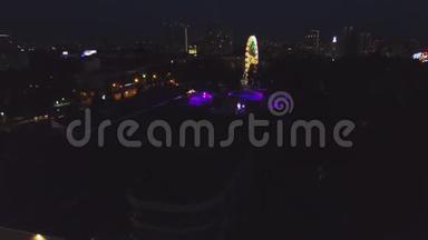 晚上在城市公园里的摩天轮。 剪辑。 夜间摩天轮发光的俯视图